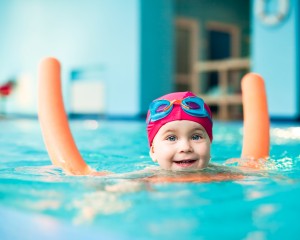 Child having fun playing games in a swimming pool.