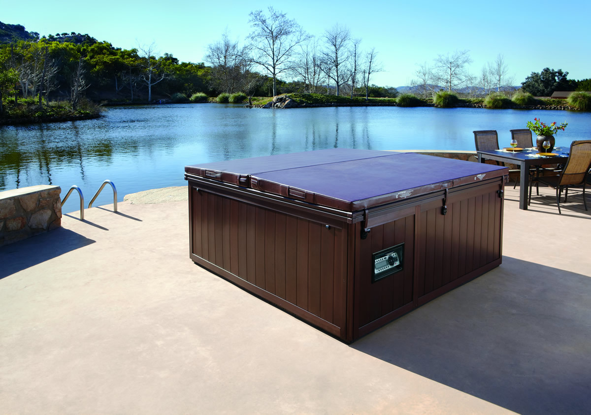 Outdoor hot tub with a cover on placed by the water.