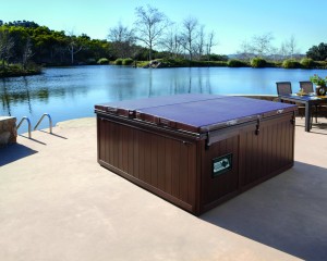 Outdoor hot tub with a cover on placed by the water.