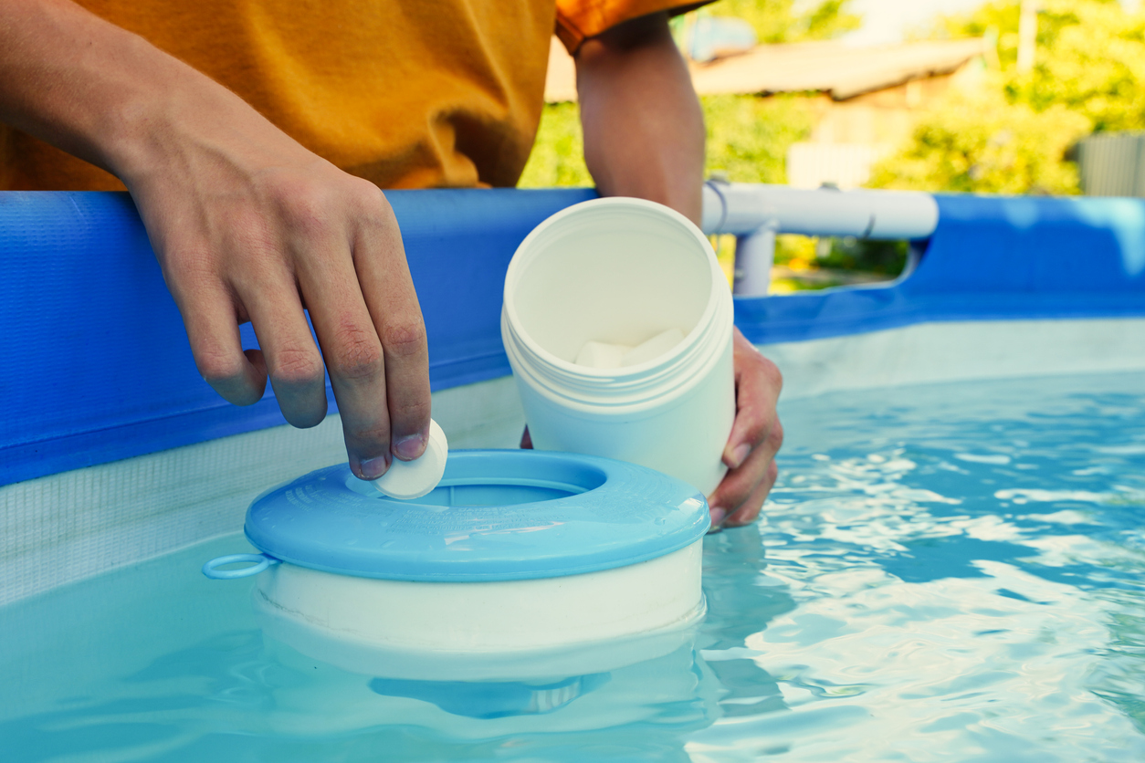 Person adding pool chemicals into their pool water.